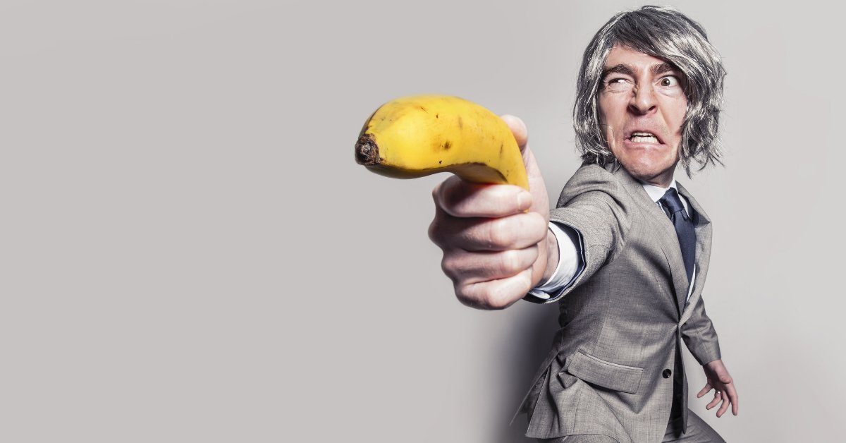 Man in suit pointing a banana like a gun