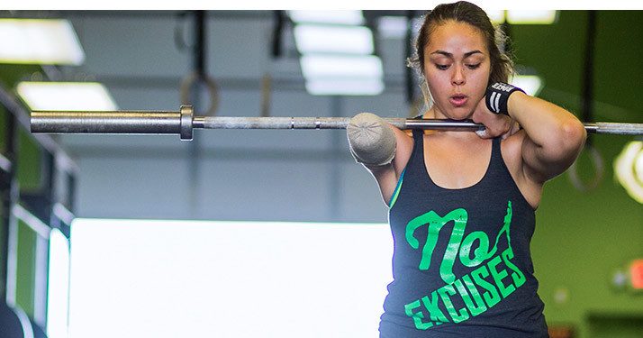 Woman lifting a barbell wearing a No Excuses tank top