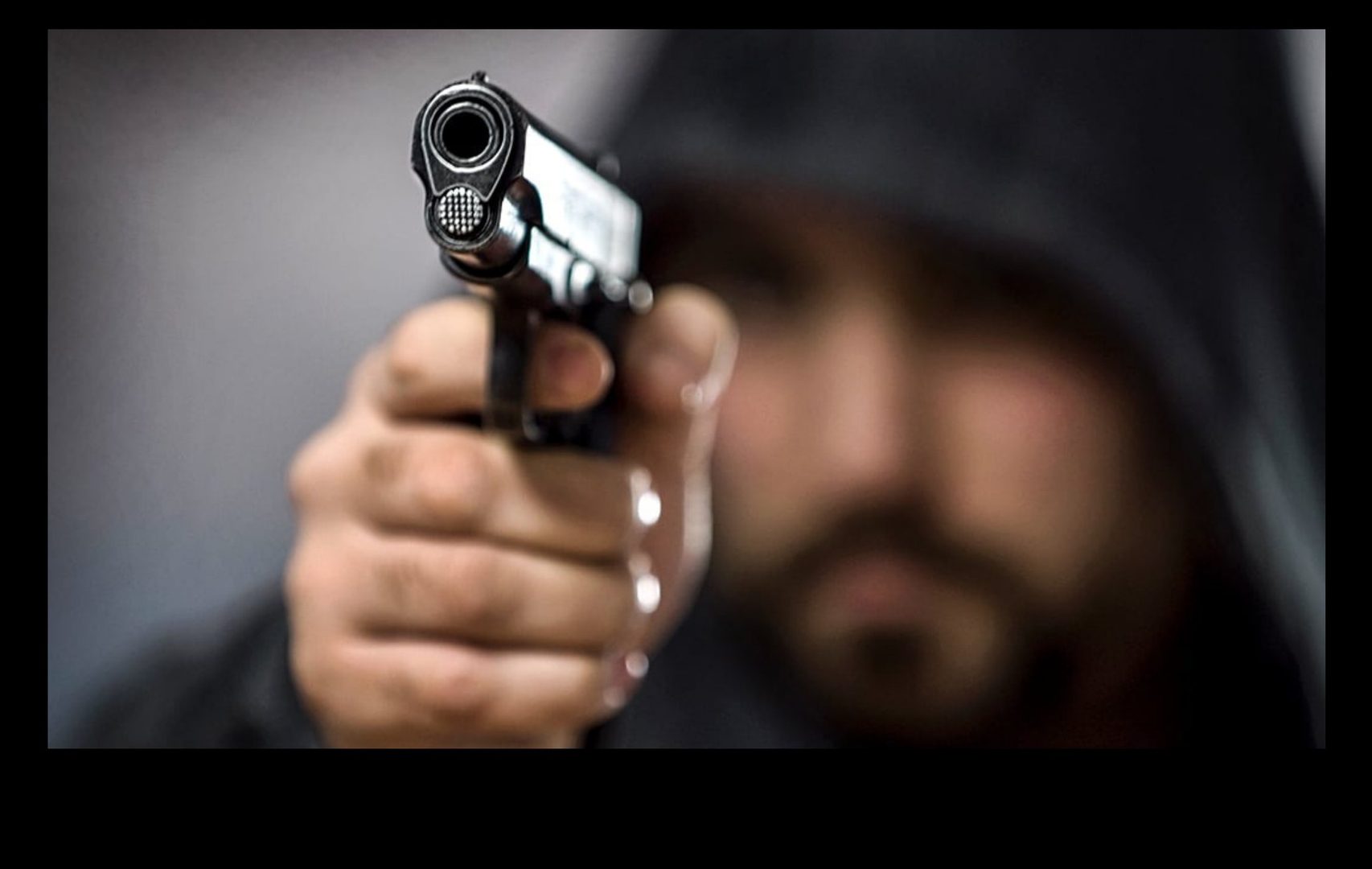 A gun pointed directly at the camera, close and focused