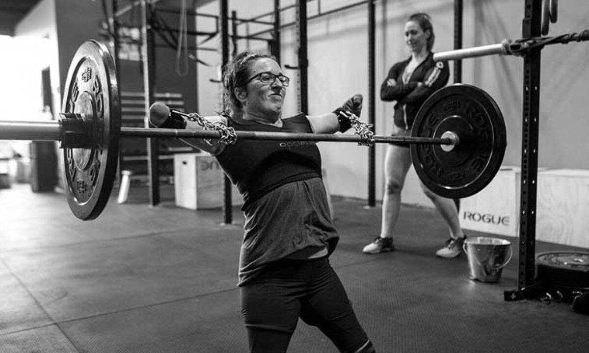 Woman powerlifting with chains on the barbell, grinding through the rep