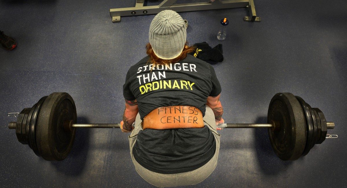 Athlete deadlifting heavy weight, shirt reading "Stronger Than Ordinary"