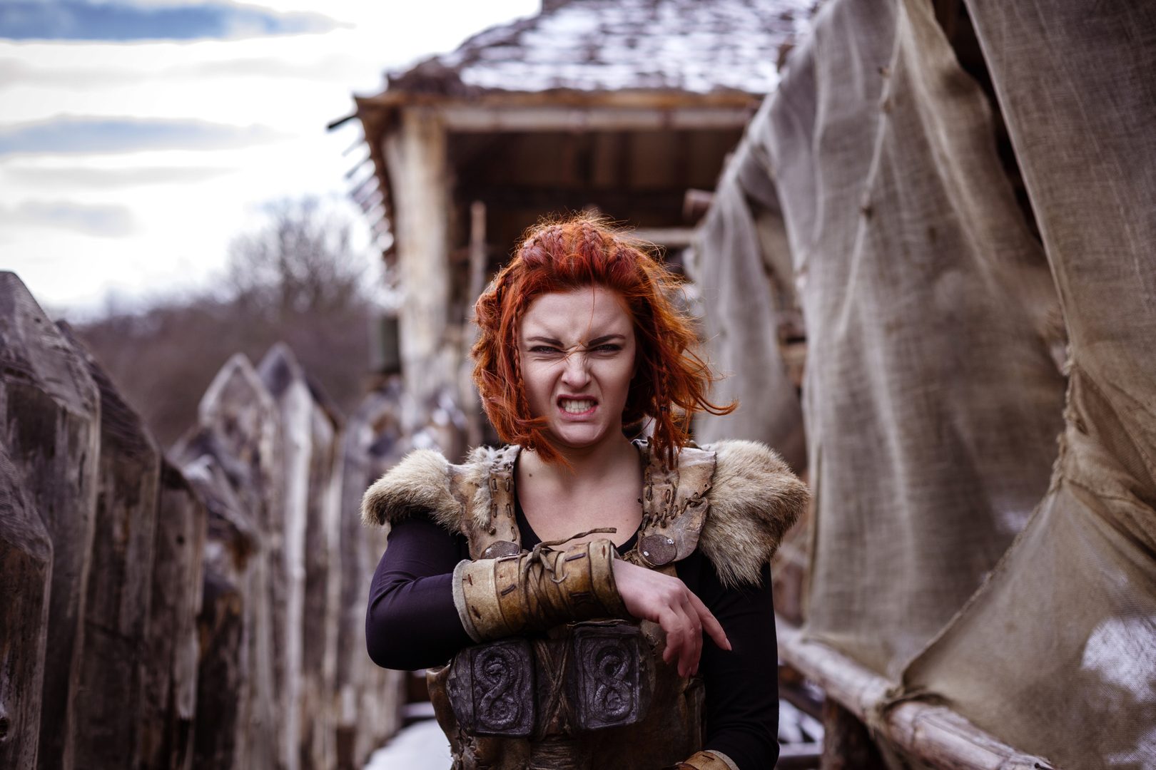 A fierce red-haired warrior woman in armor, snarling with fury